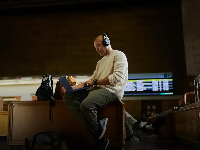 Image of a man using a Chromebook laptop  and headphones whilst on the go.